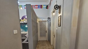 A hallway with a tiled floor, a door with a number, and a wall with flags. - Cheers Hostel Cairo (Cairo)
