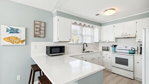 A kitchen with white cabinets, a central island, a microwave, and a stove.