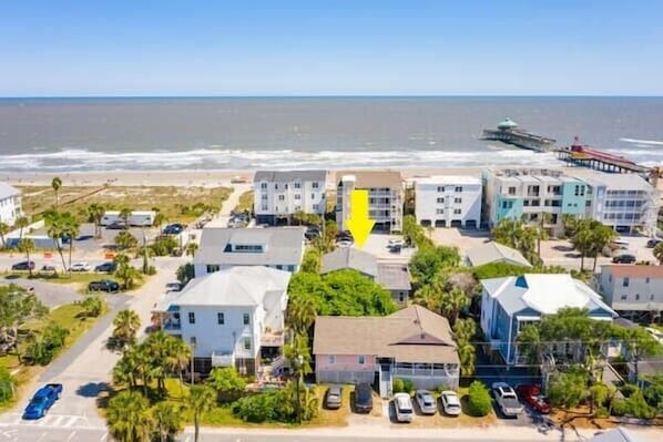 A coastal town with beachfront properties, including multi-story buildings and single-family homes with parking spaces.