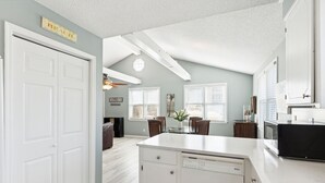 A kitchen with white cabinetry, a central island, and a dining area with a table and chairs.