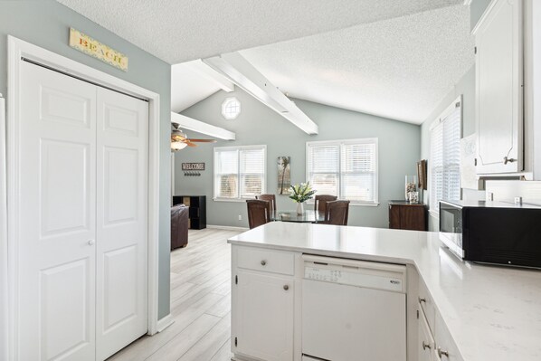 A kitchen with white cabinetry, a central island, and a dining area with a table and chairs.