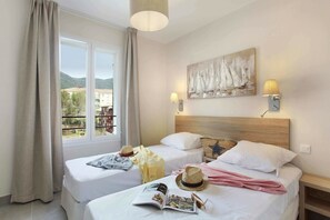 A hotel room with two beds, a large window with curtains, a painting on the wall, and a lamp. - Modern Coastal Escape (Cavalaire sur Mer)