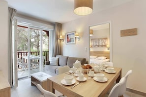 A modern hotel room with a dining area, a sofa, and a balcony with outdoor seating. - Modern Coastal Escape (Cavalaire sur Mer)