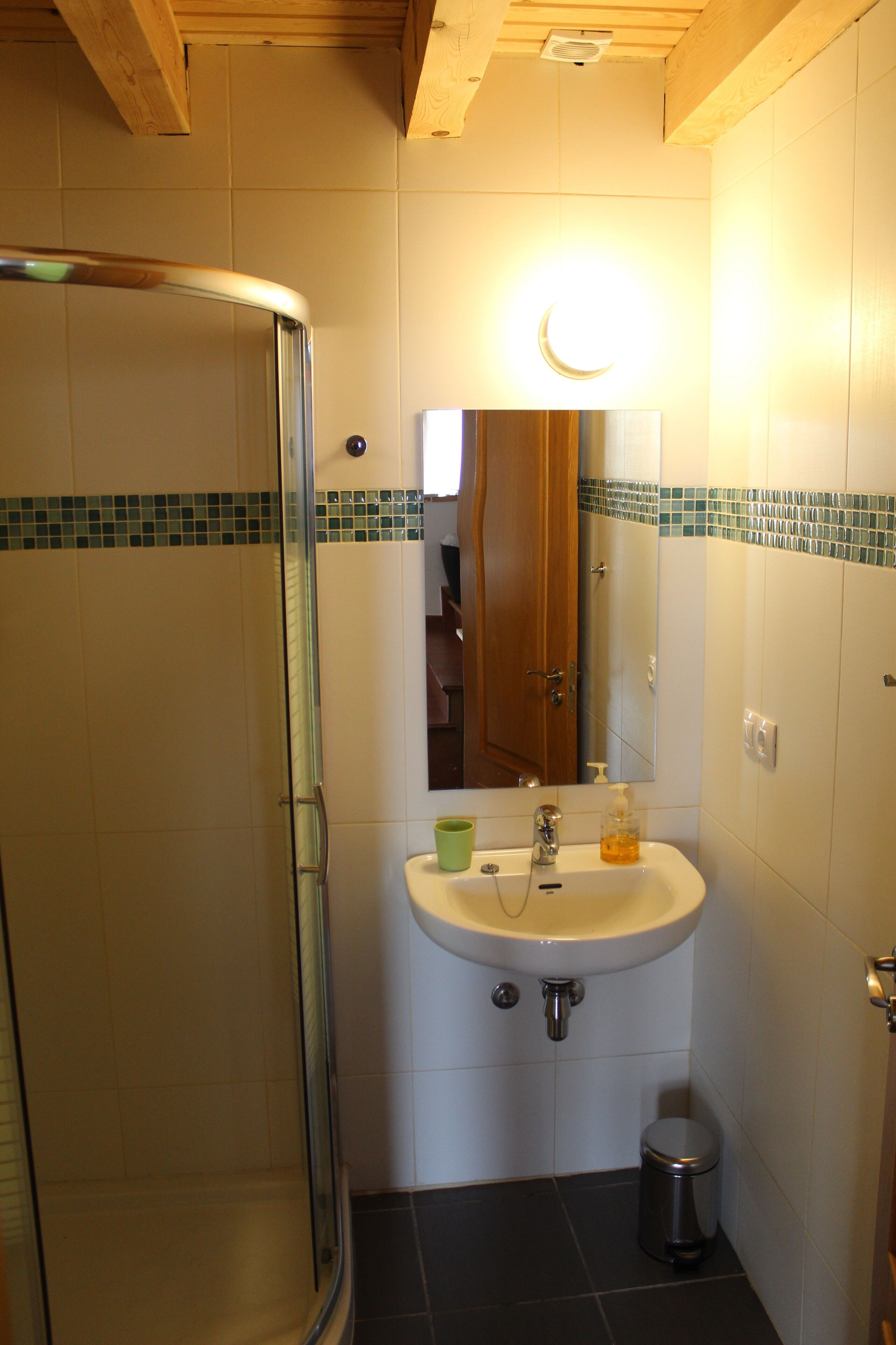 Une salle de bain avec une douche à parois de verre, un lavabo avec un miroir et un sol carrelé.