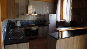 A compact kitchen with a stove, oven, microwave, and refrigerator.
