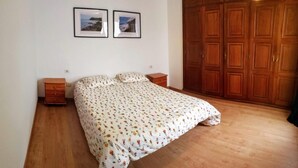 A bedroom with a bed, wooden wardrobe, two framed pictures on the wall, and a small wooden nightstand. - Centric Three Bedroom Flat in Santa Cruz 5B (Santa Cruz de Tenerife)