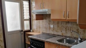 A kitchen with granite countertops, a stainless steel sink, wooden cabinets, and a built-in oven. - Centric Three Bedroom Flat in Santa Cruz 5B (Santa Cruz de Tenerife)