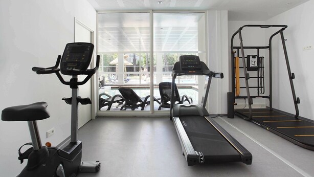 A gym with treadmills, an elliptical, and a weight machine. - Cozy & Contemporary Stay (Cavalaire sur Mer)