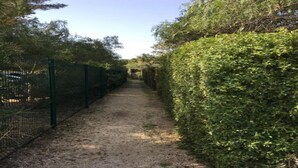 A gravel path flanked by dense hedges and a metal fence. - Cozy & Contemporary Stay (Cavalaire sur Mer)