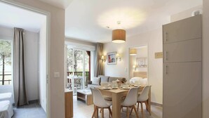 A modern dining area with a wooden table and chairs, a sofa, and a balcony with a view. - Cozy & Contemporary Stay (Cavalaire sur Mer)