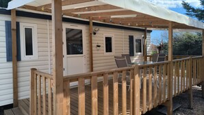 Una terraza cubierta de madera con pérgola, una mesa de vidrio y sillas.