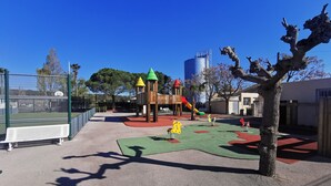 Un parque infantil con tobogán, estructuras de escalada y zona vallada.