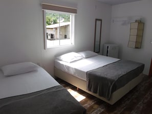 Une chambre avec deux lits, une fenêtre, un miroir et un radiateur.