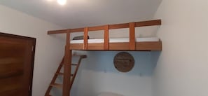 Een stapelbed met een houten ladder, een ronde decoratie aan de muur en een deur.