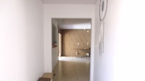 Un couloir avec un banc en bois, un mur en briques et, au fond, un coin repas.