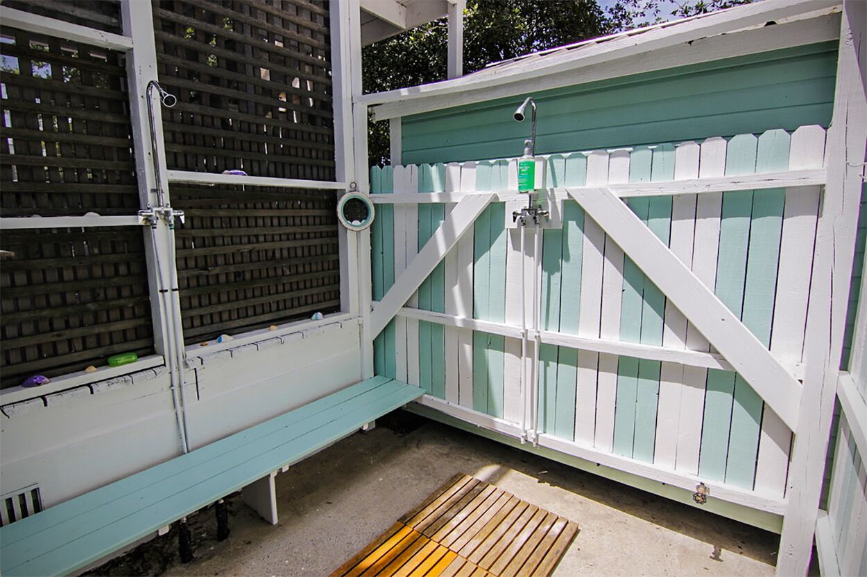 A small, enclosed outdoor area with a bench, a metal gate, and a green wall.
