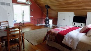 Un dormitorio con una cama, televisión, techo de madera y pared roja.