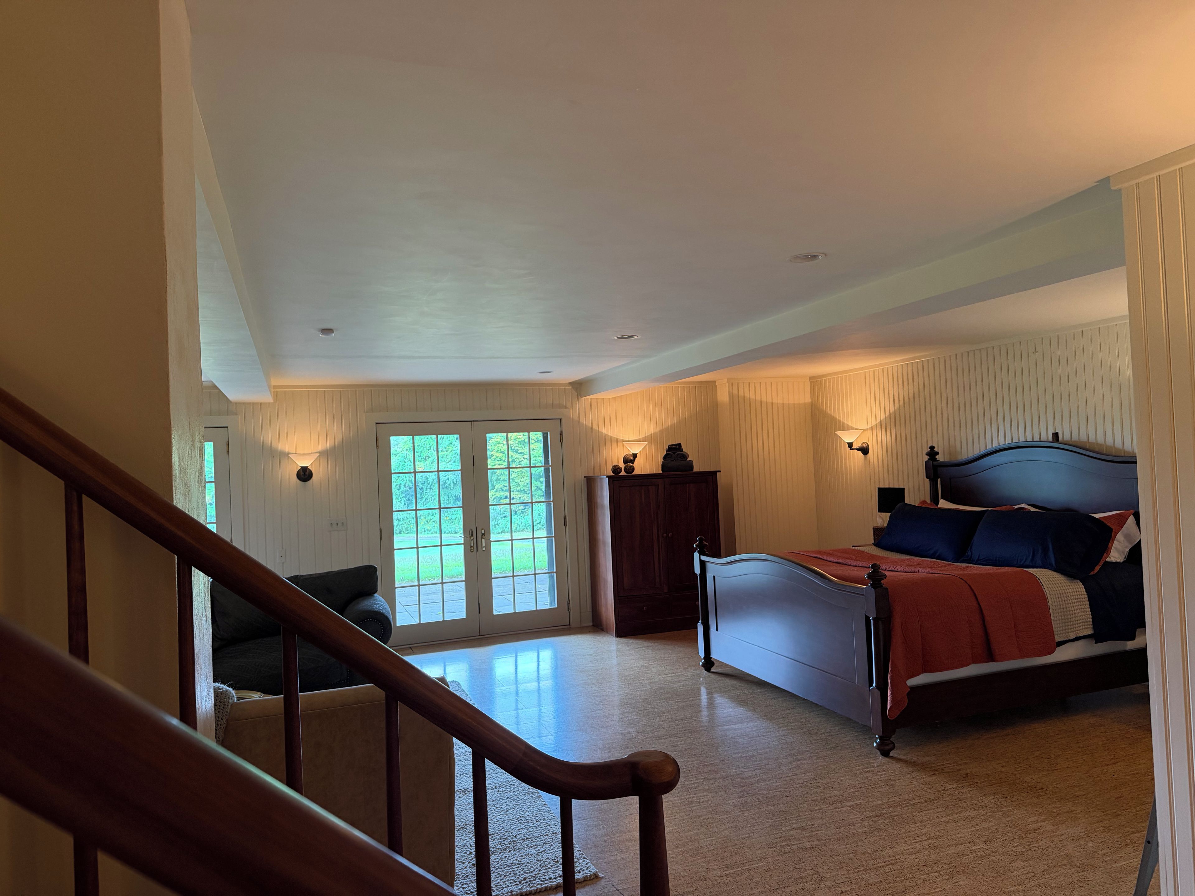 A bedroom with a bed, a dresser, a nightstand, and a window with a view.