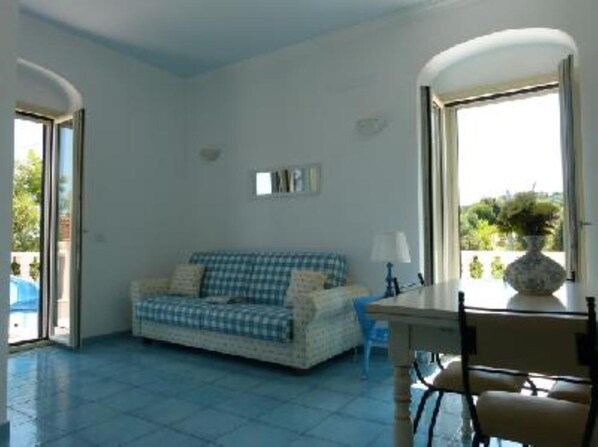 A room with a checkered sofa, a table with a lamp, and a vase with flowers. - CIELO apartment in an old farmhouse (Rodi Garganico)