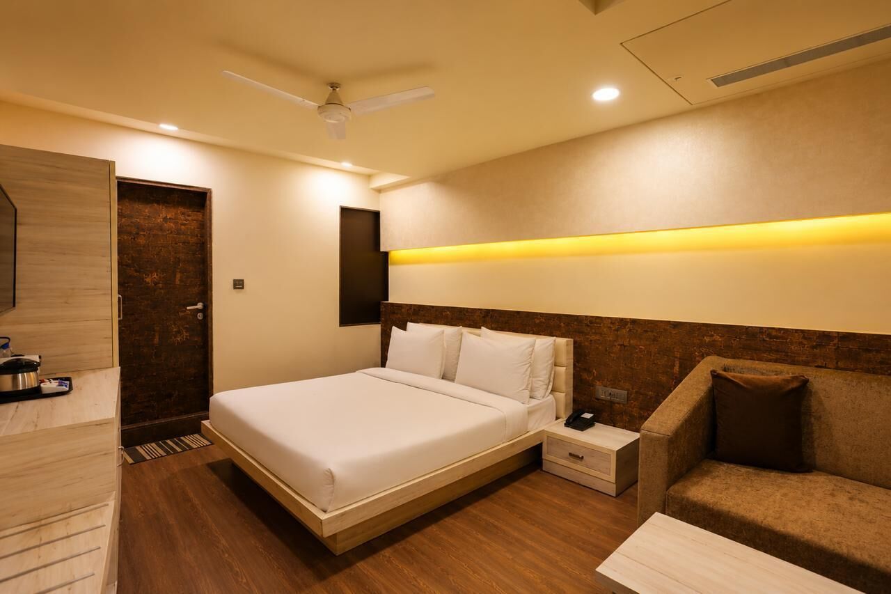 A modern hotel room with a large bed, bedside tables, a sofa, and a ceiling fan.