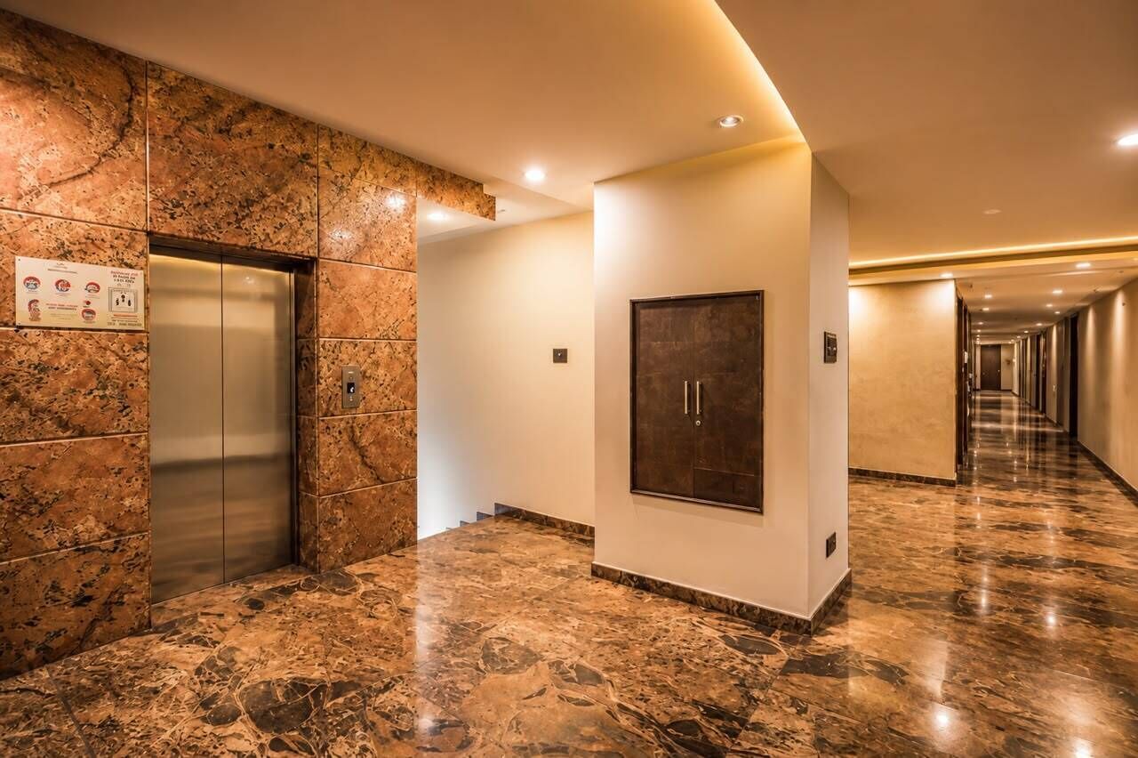 A hotel corridor with marble flooring, an elevator, a door, and a long hallway.