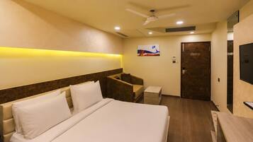 A hotel room with a bed, a desk, a chair, a television, and a door.