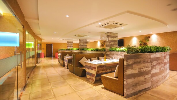 Un restaurant moderne avec des banquettes, un long comptoir et un mur décoratif agrémenté de plantes.