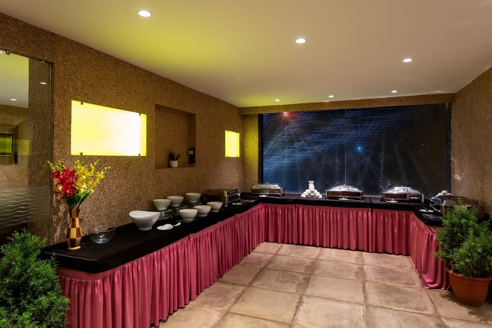 A buffet setup with a long counter, multiple serving dishes, and a decorative wall with a textured pattern.