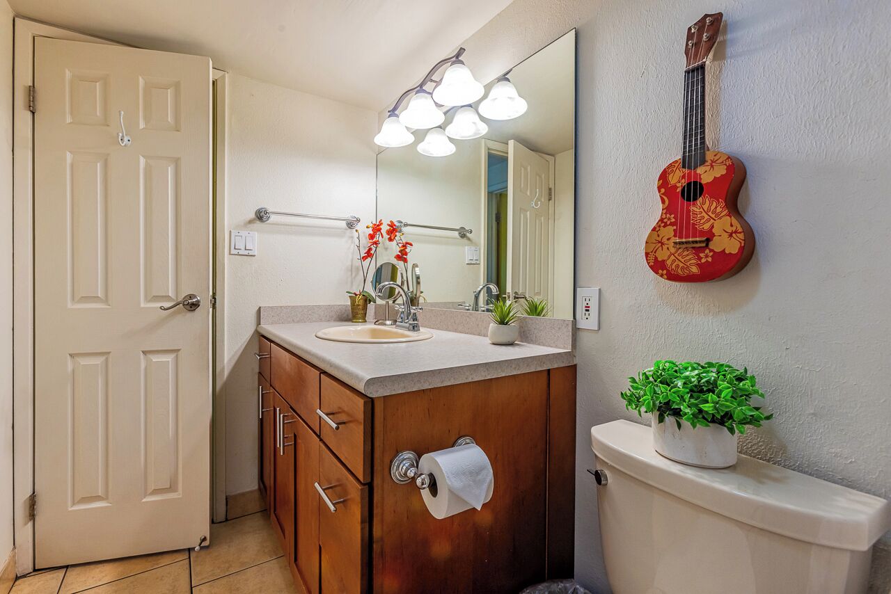 Une salle de bain avec un meuble-lavabo en bois, des toilettes, un miroir et une guitare accrochée au mur.