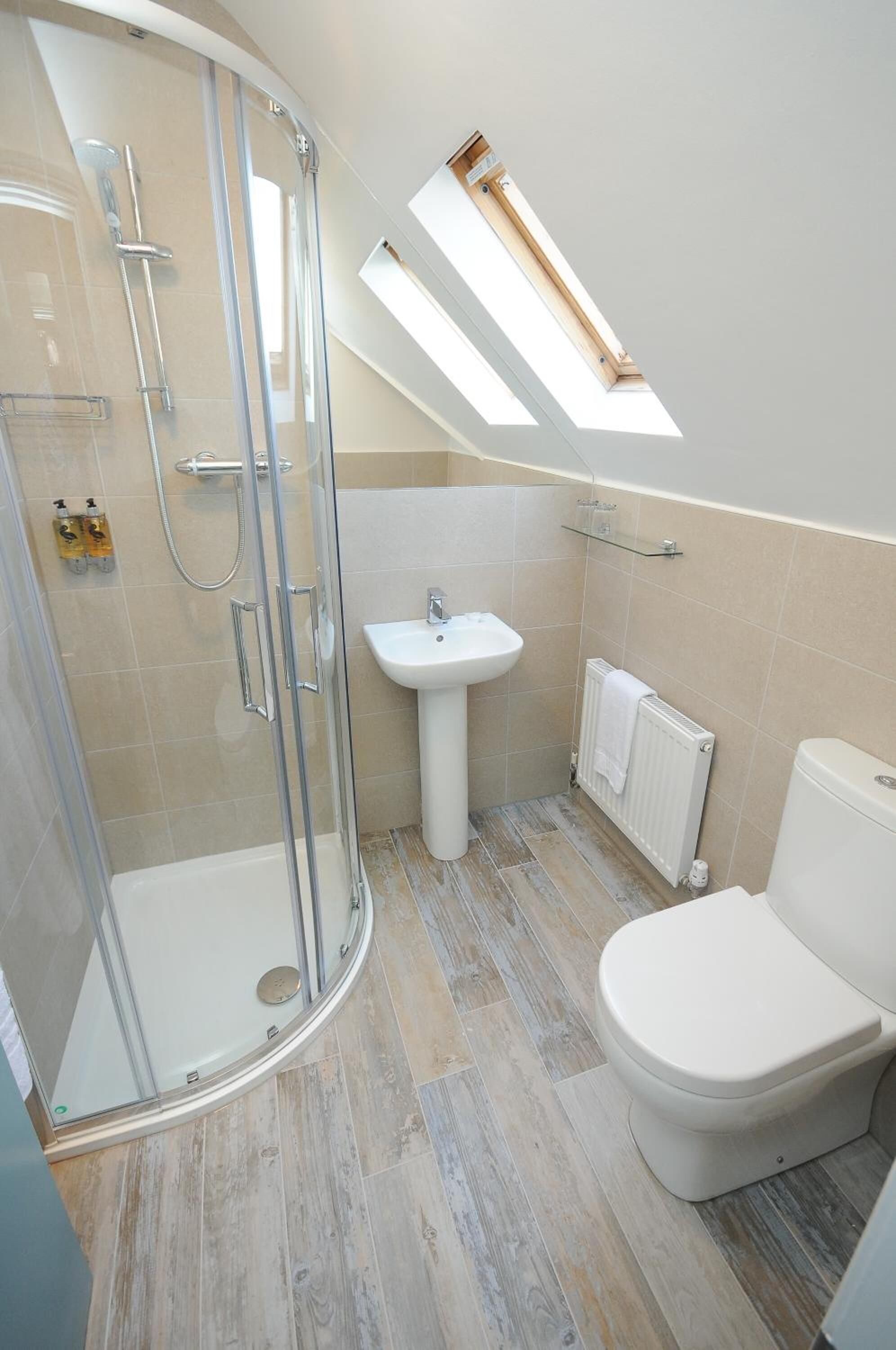 A modern bathroom with a glass shower enclosure, a pedestal sink, and a toilet.