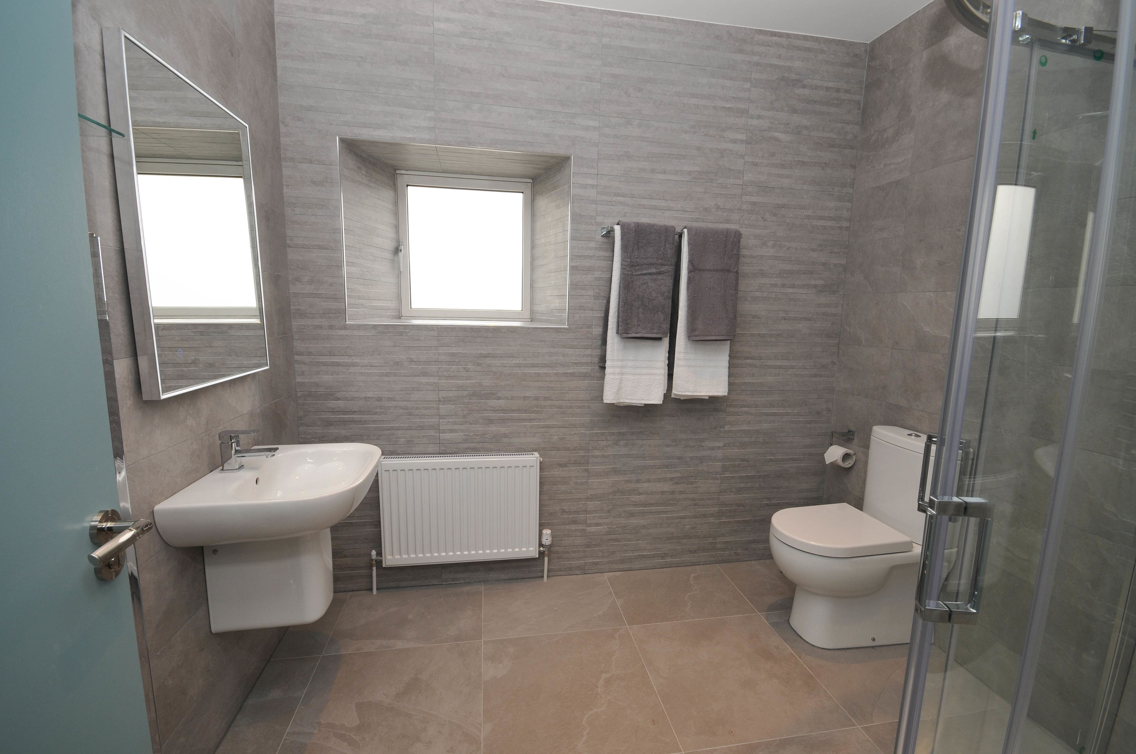 A modern bathroom with a sink, toilet, and shower.
