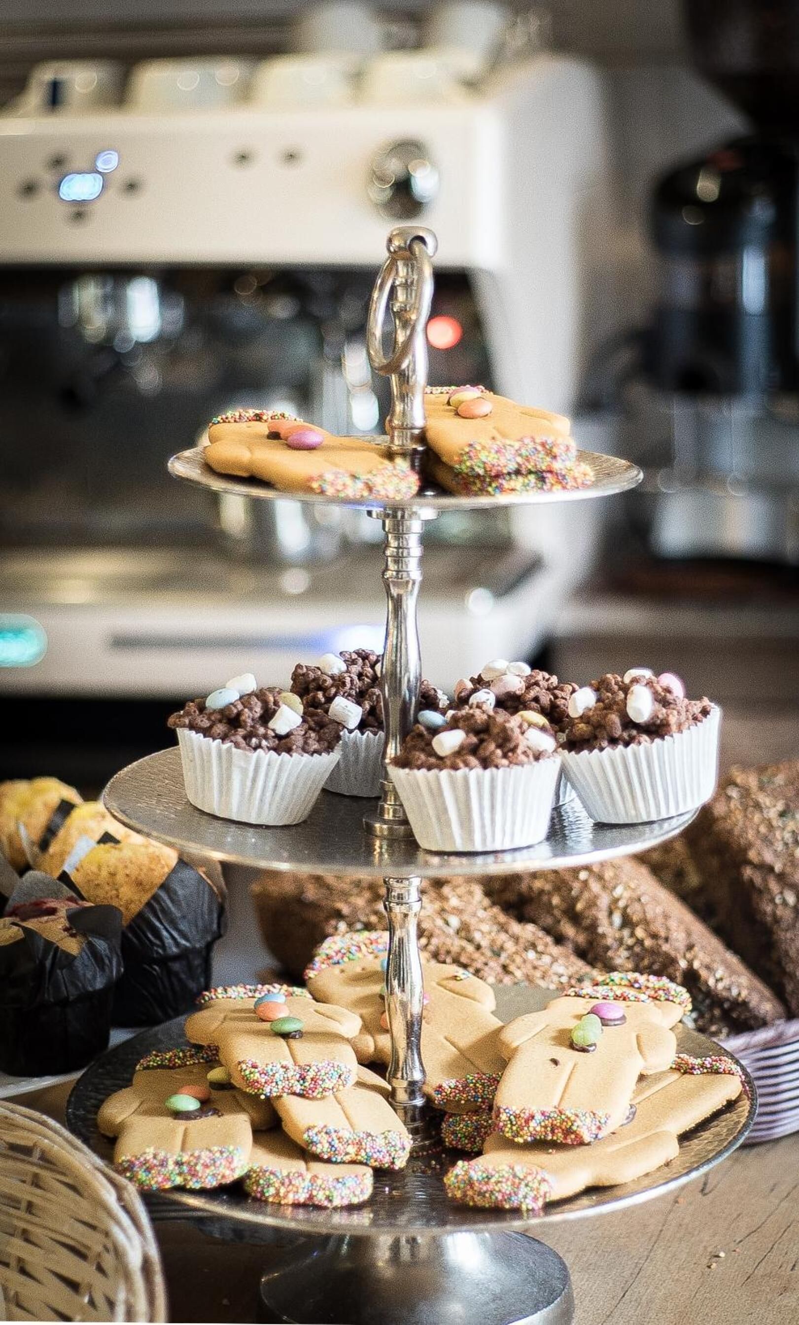 A three-tiered dessert stand with various cookies and cupcakes.