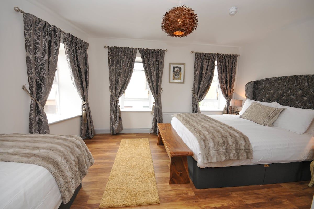 A bedroom with a large bed, a bench, and a wooden floor.