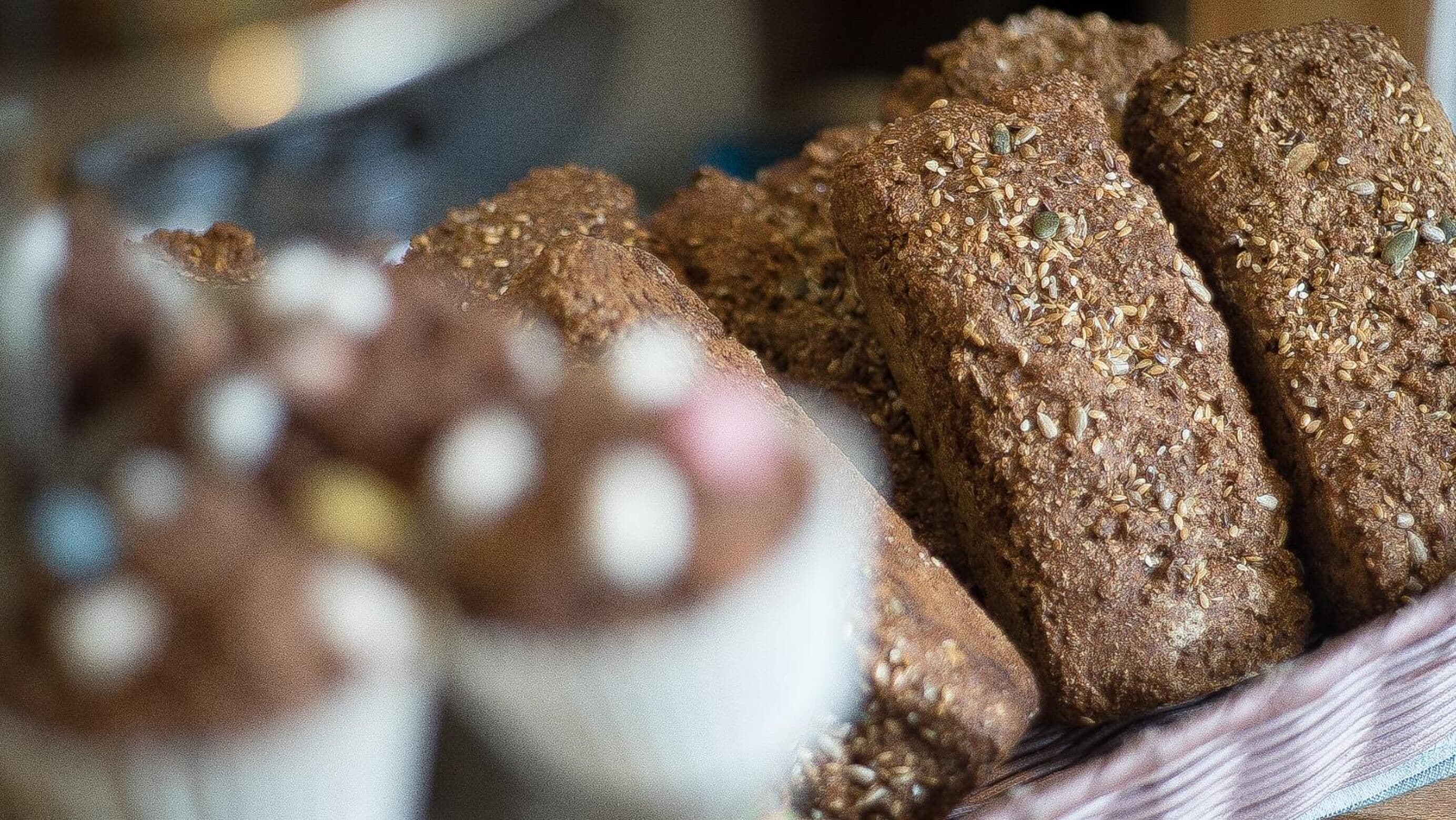 A basket of multi-grain bread with seeds and grains.