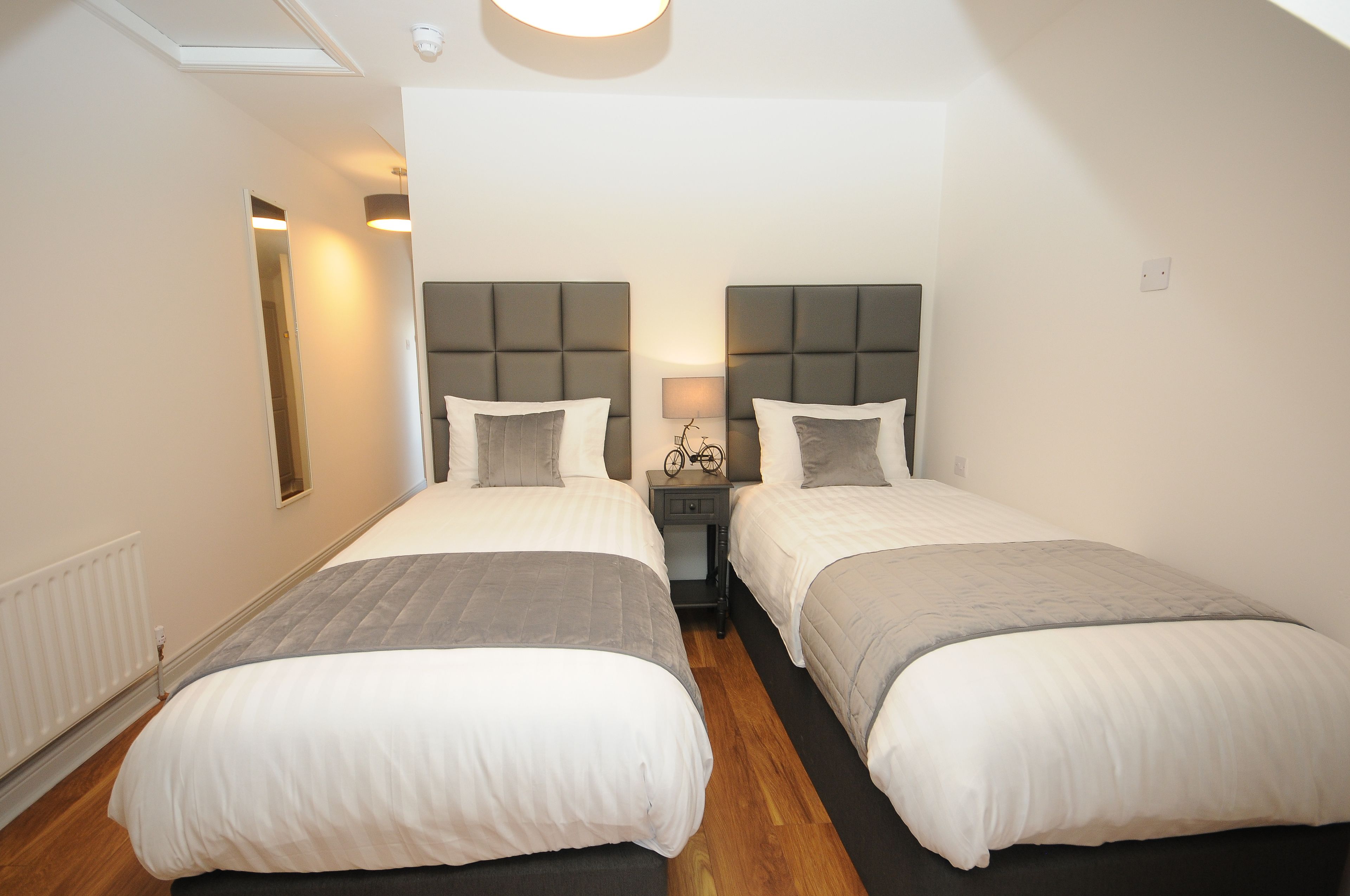 Une chambre double avec deux lits, une table de chevet avec une lampe et un radiateur.