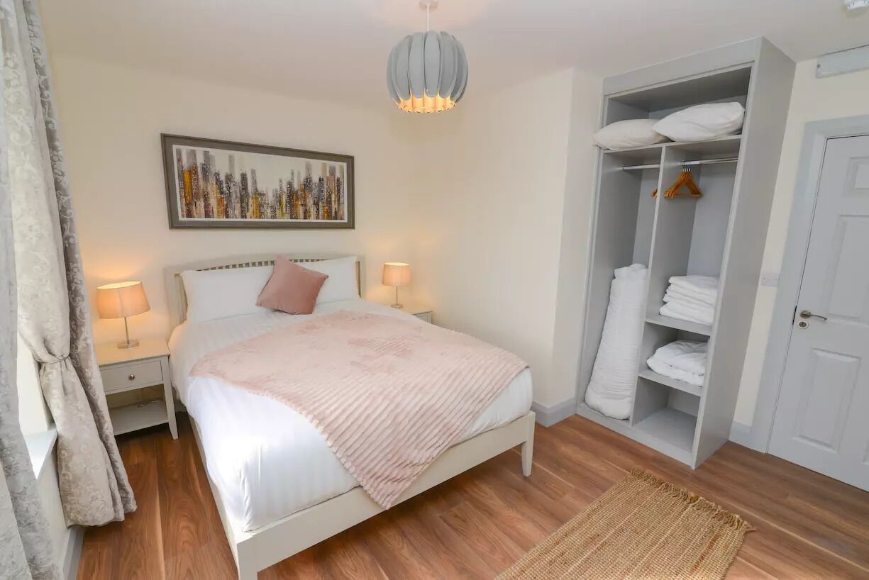 Ein Schlafzimmer mit Bett, Nachttischlampen, einem Kleiderschrank und einem Stadtbild an der Wand.
