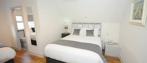 Una camera da letto con un letto grande, un comodino, uno specchio e una porta che dà su un bagno.