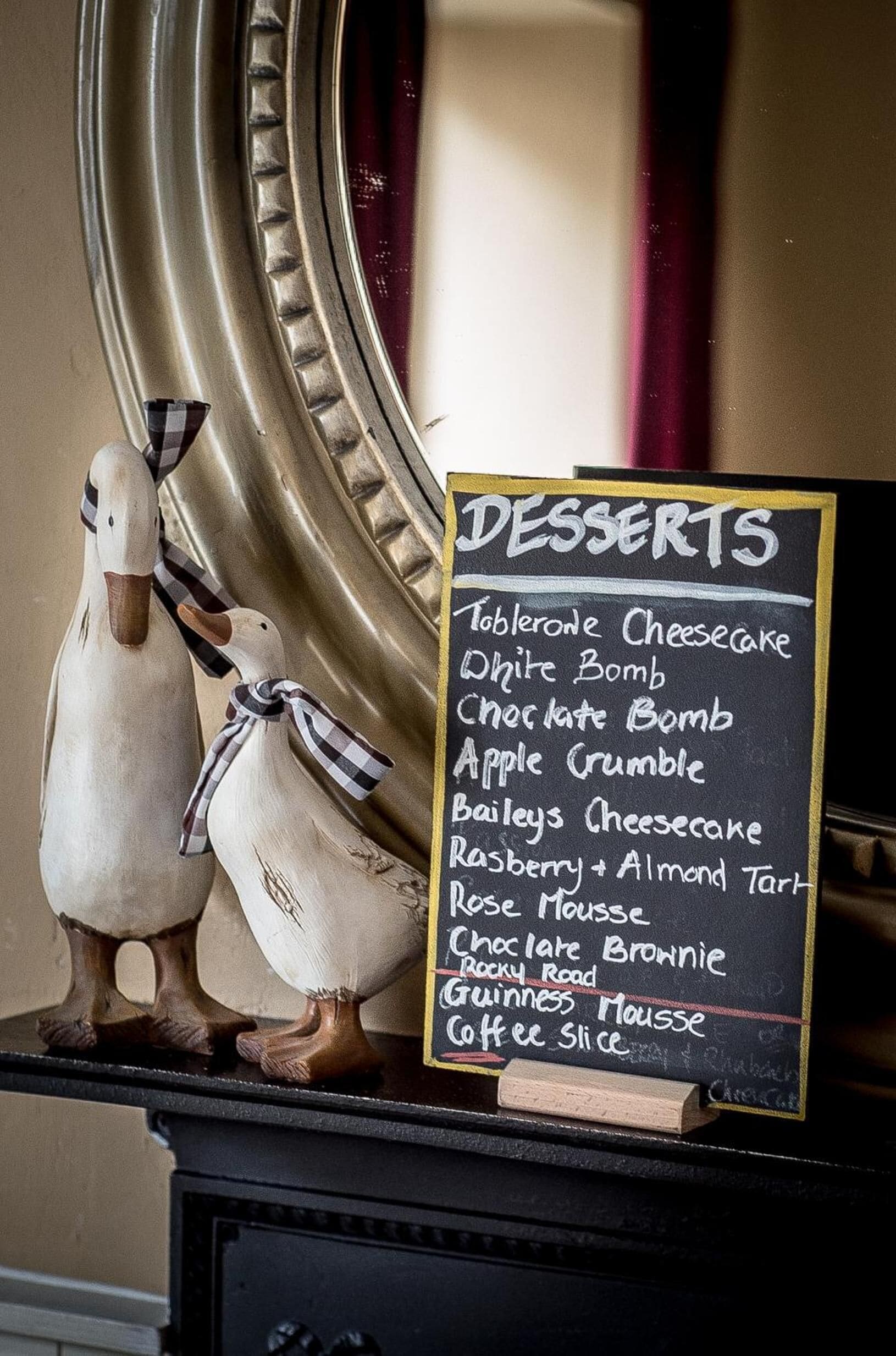 Una pizarra muestra el menú de postres, incluyendo Cheesecake Tablée y White Bomb.