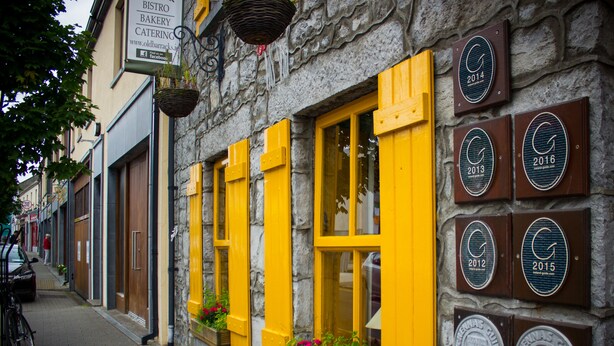 A stone building with yellow shutters and multiple plaques indicating awards from 2012 to 2016. - Lodge at The Old Barracks (Athenry)