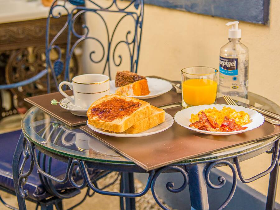 Una mesa de desayuno con una taza, tostadas, huevos revueltos y jugo de naranja.