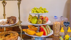 A buffet table with various food items including cakes, fruits, and cereals. - Pousada Dom Petrópolis (Petrópolis)