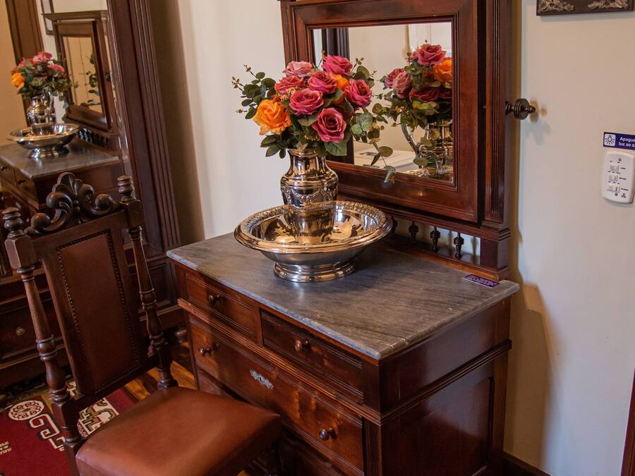 A wooden dresser with a mirror, a vase of flowers, and a tray.