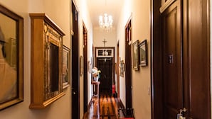 A hallway with wooden floors, framed pictures, and a chandelier. - Pousada Dom Petrópolis (Petrópolis)