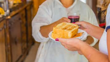 A person in a white apron holding a plate with a pastry.