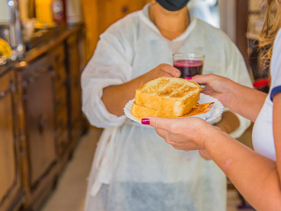 A person in a white apron holding a plate with a pastry.