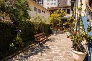 A stone-paved pathway leading to a bench and a reception area with a sign. - Pousada Dom Petrópolis (Petrópolis)