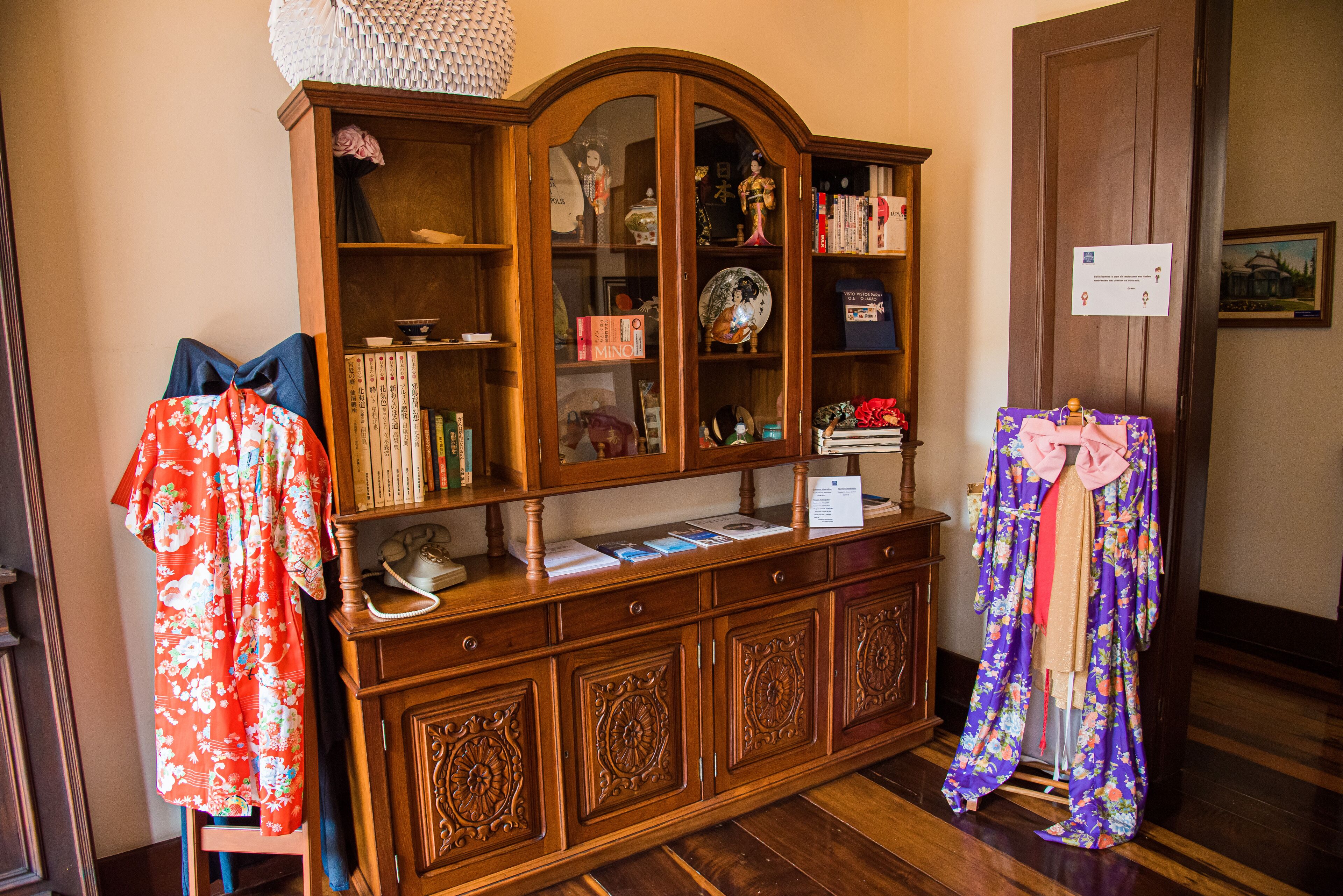 A wooden cabinet with glass doors, books, and decorative items.