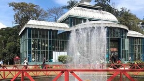 A dog sitting in front of a fountain with a red metal fence. - Pousada Dom Petrópolis (Petrópolis)