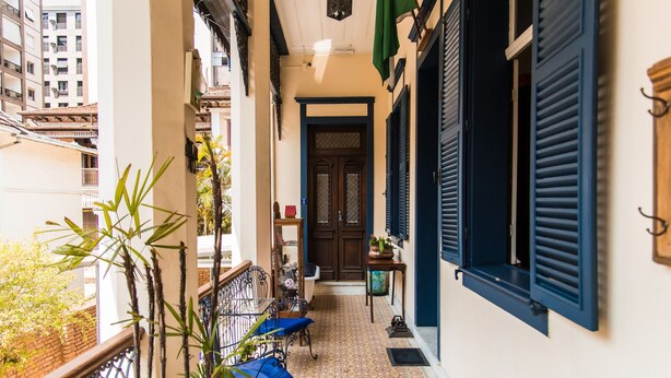 A narrow corridor with a tiled floor, a wooden door, and a small table with a potted plant. - Pousada Dom Petrópolis (Petrópolis)