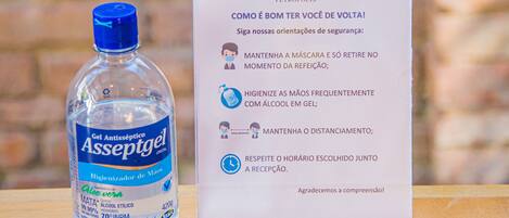 A bottle of Asseptgel hand sanitizer and a sign with safety guidelines.